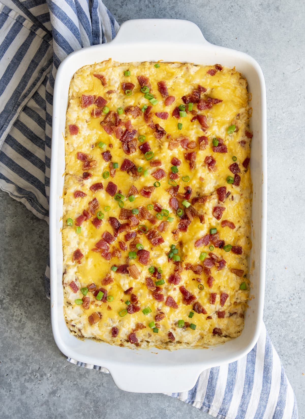 An overhead photo of chicken and rice casserole topped with melted cheese, and bacon pieces.