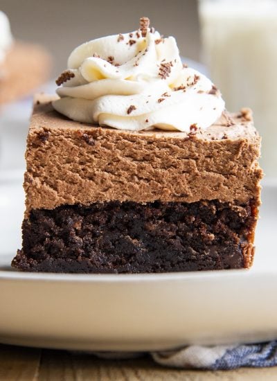 A close up of a brownie topped with french silk chocolate mousse, and a flower of whipped cream.