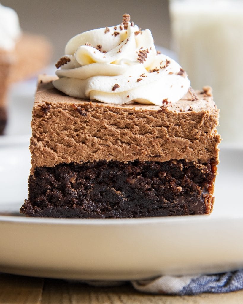 A close up of a brownie topped with french silk chocolate mousse, and a flower of whipped cream.