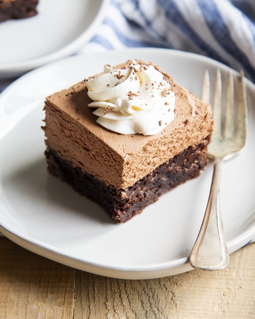 A French silk brownie topped with french silk mousse topped with whipped cream on a plate.