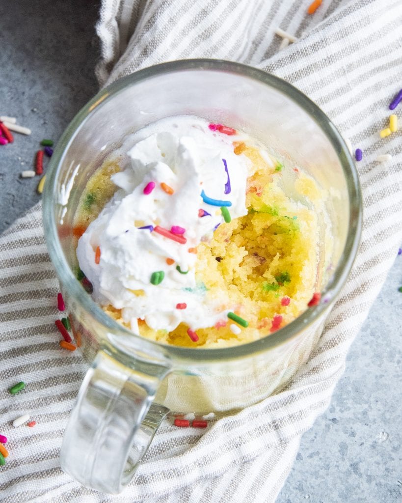 A funfetti mug cake with bites taken out of it, showing the crumb of the cake.