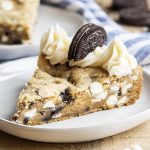 A piece of Oreo cookies and cream cookie cake topped with frosting.