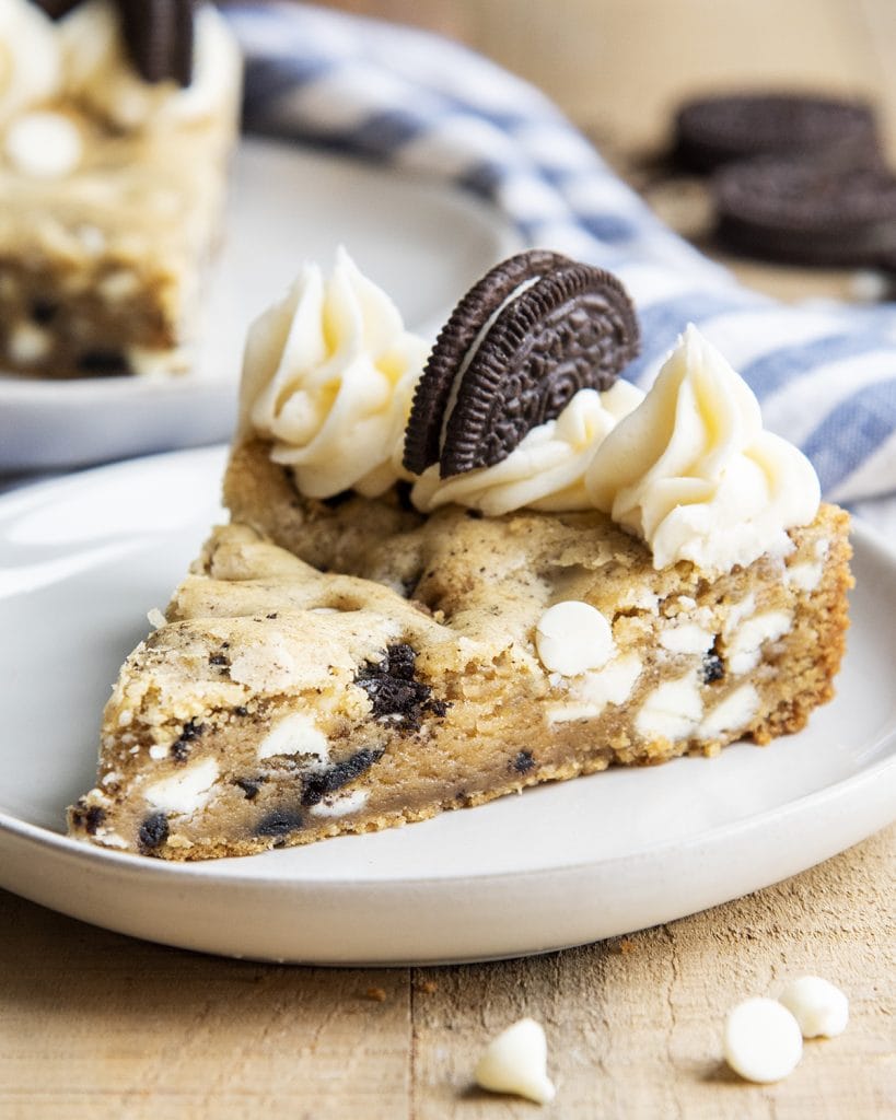 A piece of Oreo cookies and cream cookie cake topped with frosting.