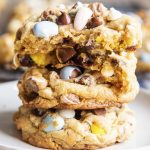 A stack of large cookies full of chocolate chips and cadbury mini eggs.