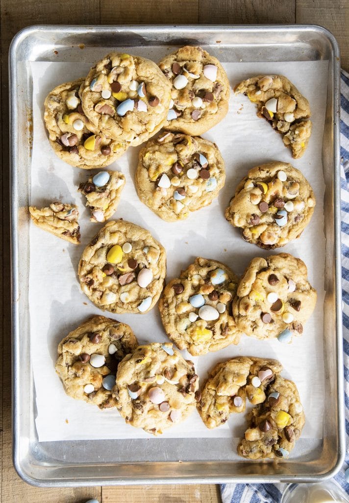 Large cookies filled with chocolate chips and cadbury mini eggs on a cookie sheet.