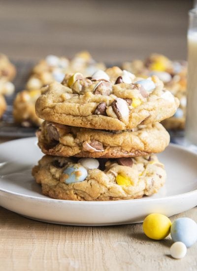 A stack of three large cadbury mini egg cookies on a plate.