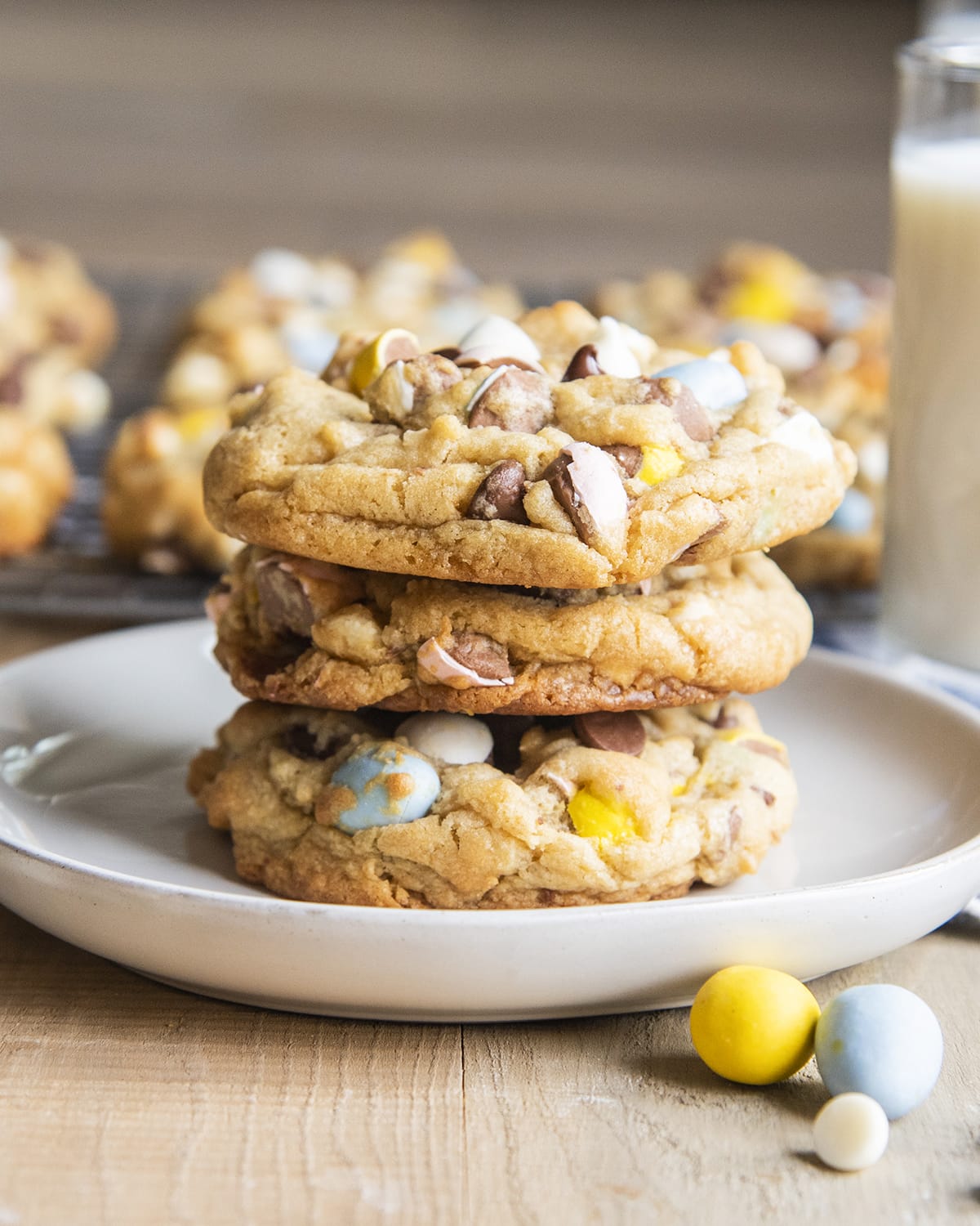 A stack of three large cadbury mini egg cookies on a plate.