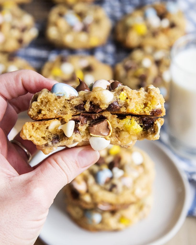 A hand holding two halves of a cadbury egg cookie.