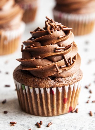 A chocolate cupcake topped with chocolate frosting, and chocolate jimmie sprinkles.