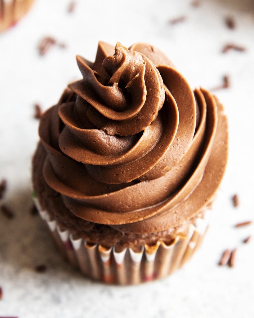 A close up of chocolate buttercream frosting on a chocolate cupcake.