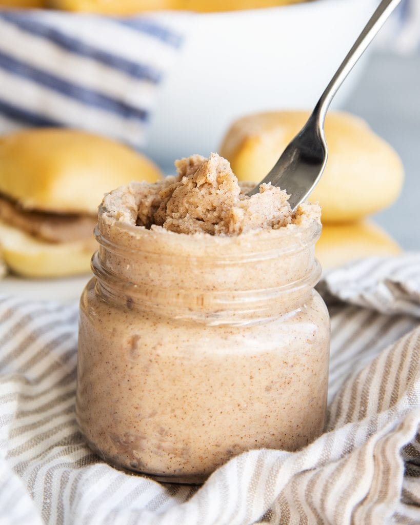 A jar of cinnamon honey butter in it with a spreading knife in it. 