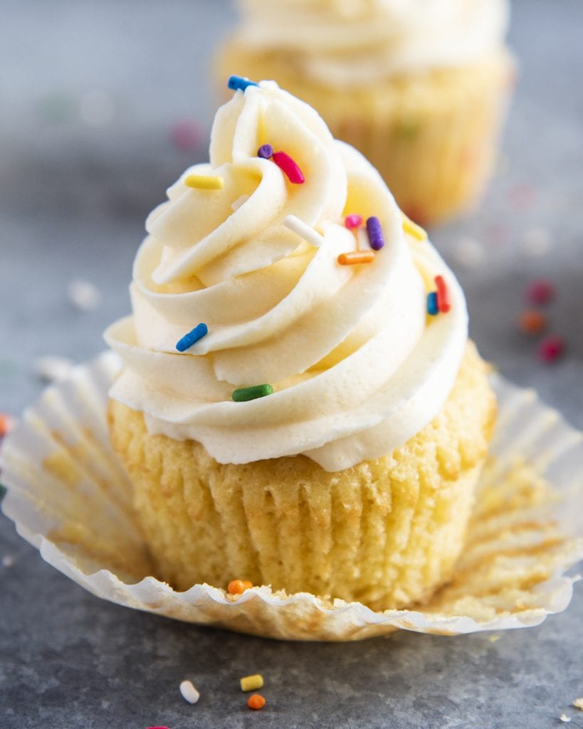 A vanilla cupcake on a cupcake liner.