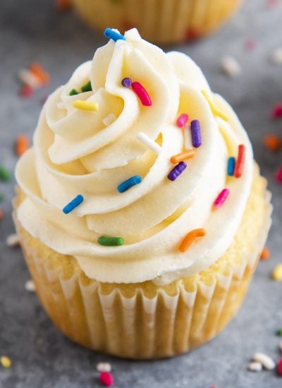 A close up of buttercream frosting topped with sprinkles on a cupcake.