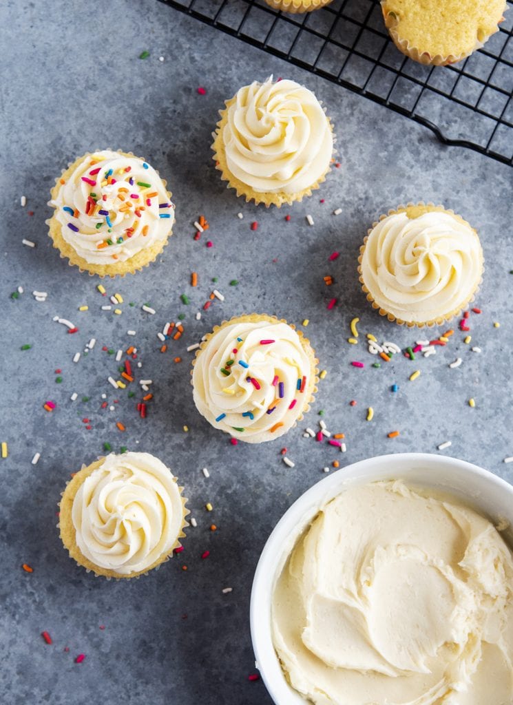 An overhead photo of buttercream frosted cupcakes and a bowl of frosting.