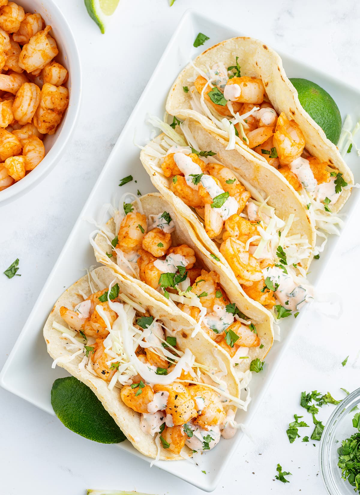 An overhead photo of a row of shrimp tacos on a plate.