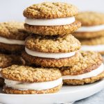 A pile of oatmeal cookie sandwiches with marshmallow frosting between them.