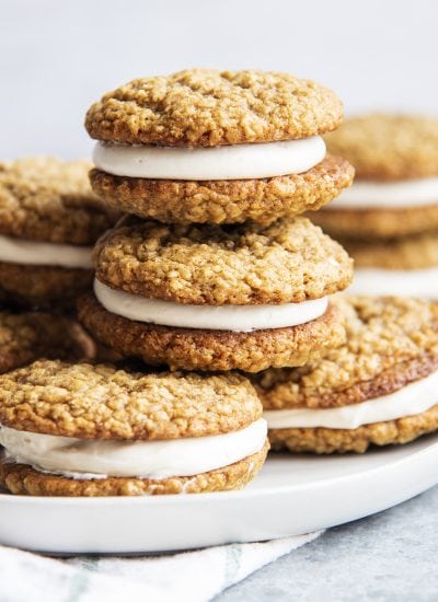A pile of oatmeal cookie sandwiches with marshmallow frosting between them.