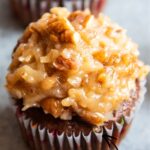 A cupcake topped with coconut pecan frosting on top.