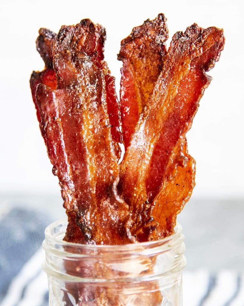 A close up of strips of brown sugar bacon in a jar.