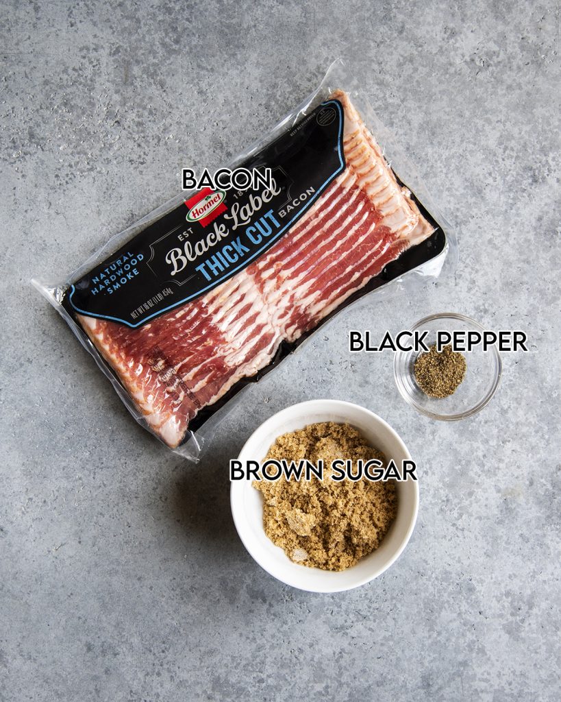 An overhead photo of the ingredients needed to make brown sugar bacon, brown sugar, black pepper, and bacon.