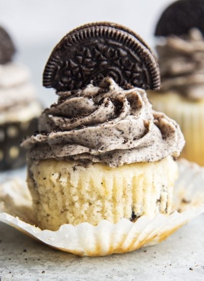 A frosted Oreo cupcake on a cupcake liner.