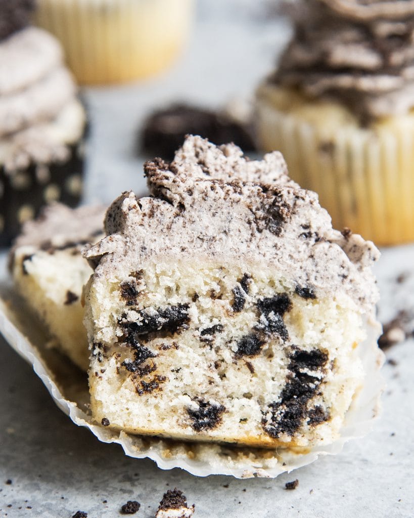 A cookies and cream cupcake cut in half showing the middle of the cupcake.