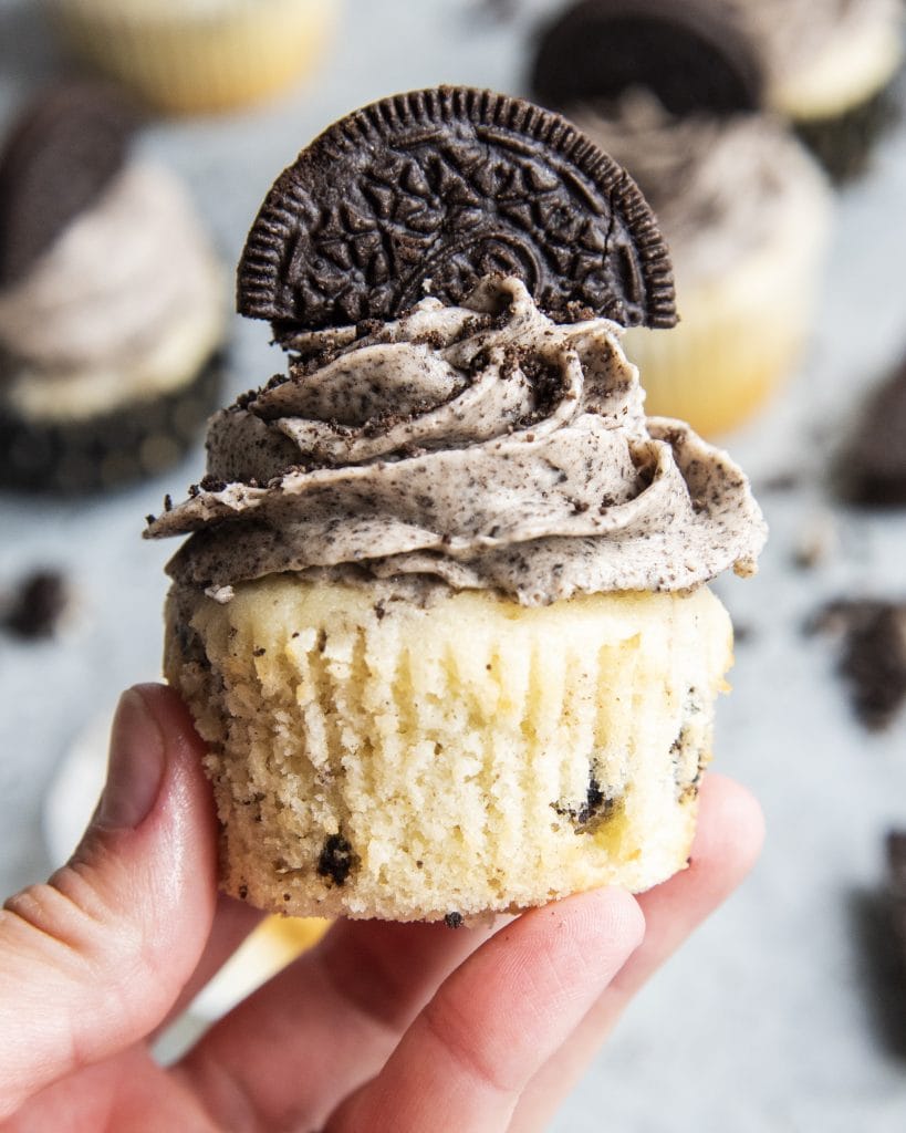 A hand holding an Oreo cupcake.