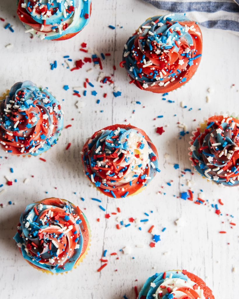 An overhead photo of cupcakes topped with swirls of red, white, and blue buttercream frosting.