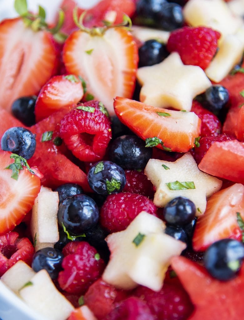 A close up of a bowl of red white and blue fruit salad.