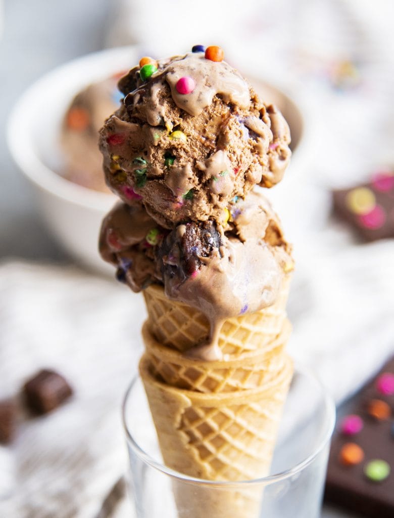 A cosmic brownie ice cream cone sitting in a glass cup.