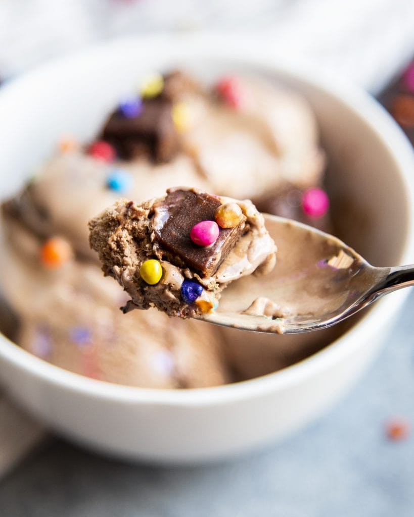 A spoonful of cosmic brownie ice cream with rainbow candied chips on the ice cream.