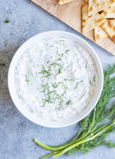 A bowl of homemade tzatziki sauce topped with fresh dil.