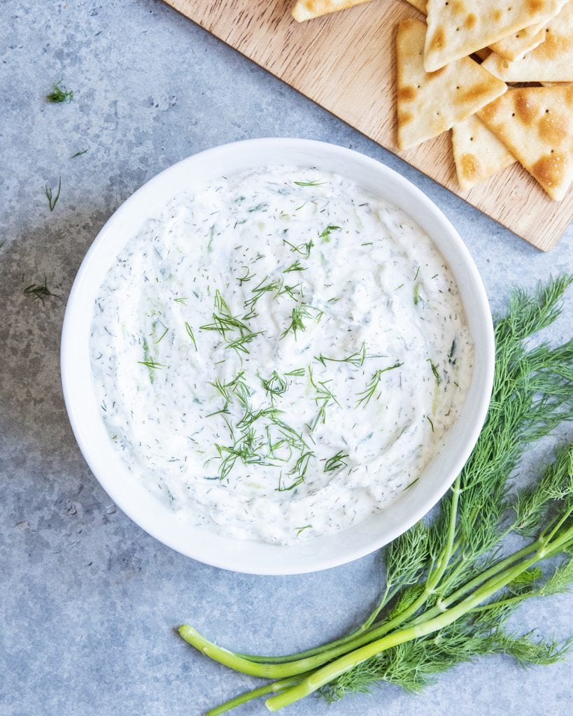 A bowl of homemade tzatziki sauce topped with fresh dil.