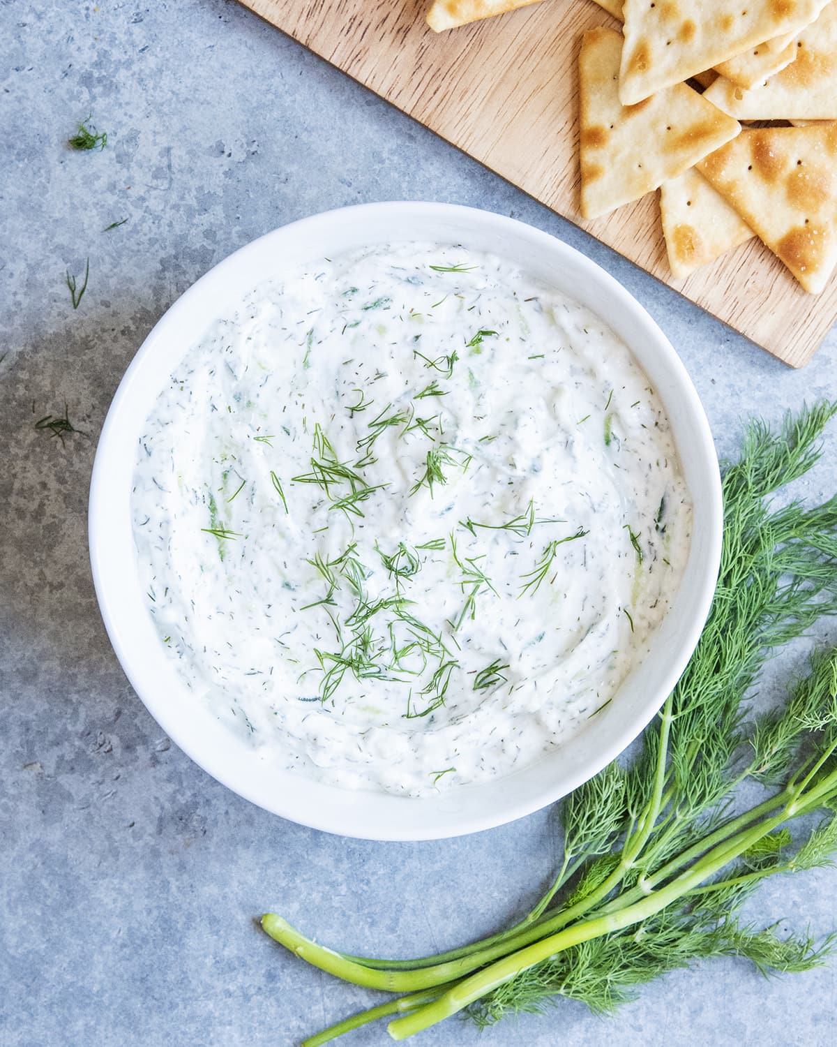 A bowl of homemade tzatziki sauce topped with fresh dil.