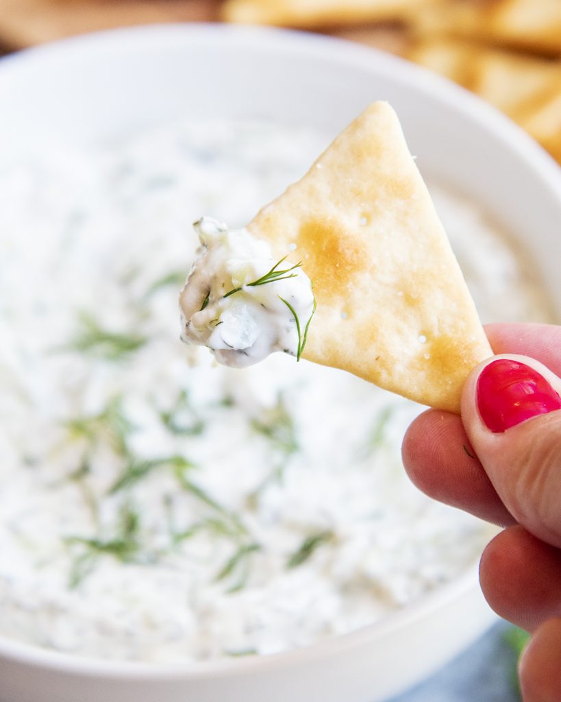 A pita chip dipped into tzatziki sauce.