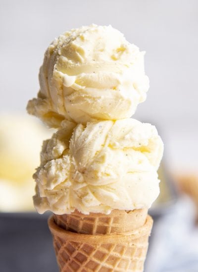 A close up of a french vanilla ice cream cone with two scoops on top.