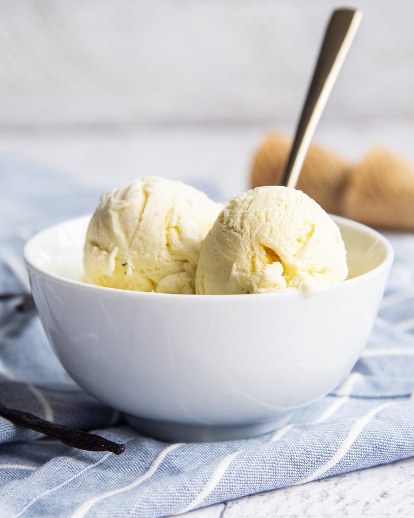 A bowl of vanilla bean ice cream with a spoon in the bowl.