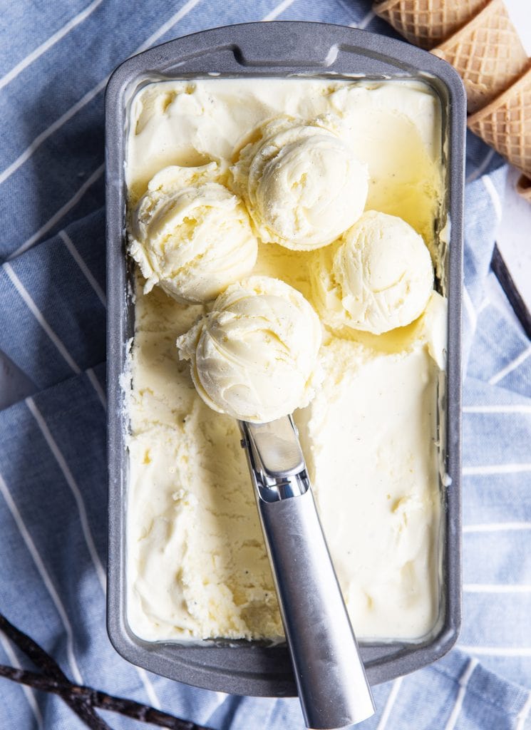 A pan of vanilla custard ice cream with scoops of ice cream on top.