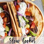 A plate of slow cooker beef gyros on pitas with a text overlay for pinterest.