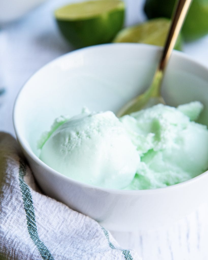 A close up of a scoop of lime sherbet in a white bowl.