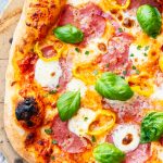 A photo of salami pizza topped with fresh basil, with the title over the top.