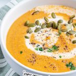 A bowl of tomato squash soup with a text block over the top for pinterest.
