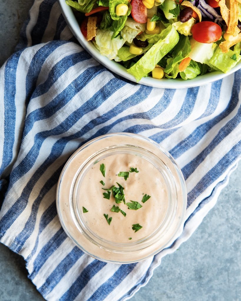 An overhead photo of a jar of BBQ Ranch Dressing next to a salad.