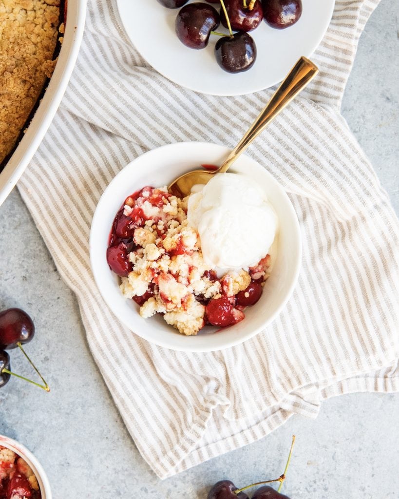 An overhead photo of a bowl of homemade cherry cobbler made with a cake mix, with a scoop of ice cream on top.