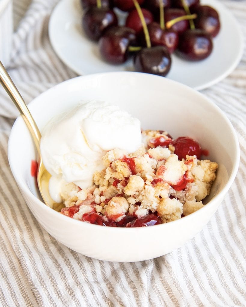 A bowl of cake mix cherry cobbler with a scoop of ice cream on top.