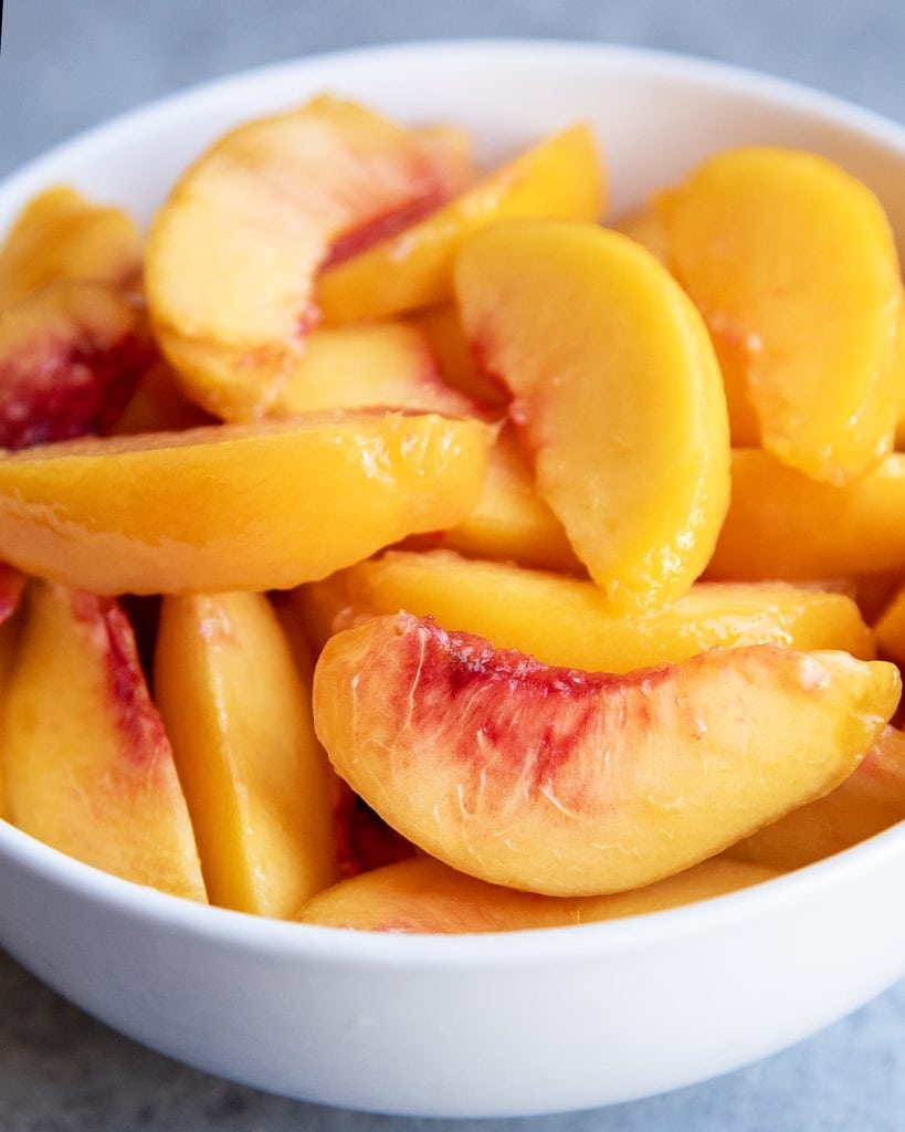 A close up of a bowl of peach slices.