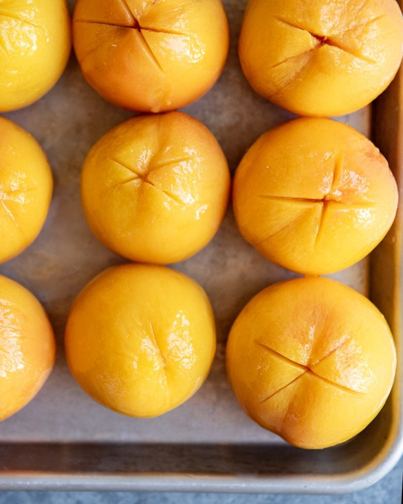 An overhead photo of rows of peeled peaches on a tray.