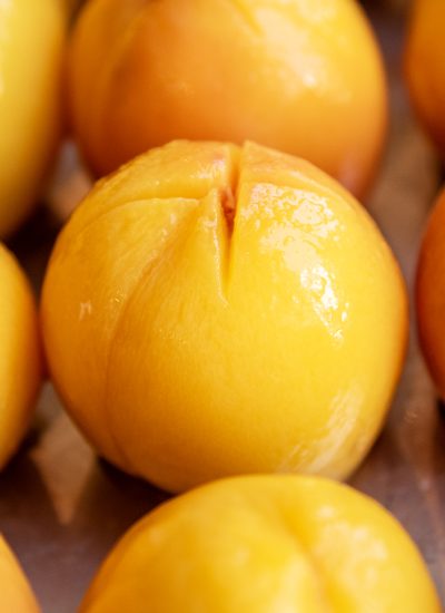 A shiny peeled peach with an x cut out on the top.
