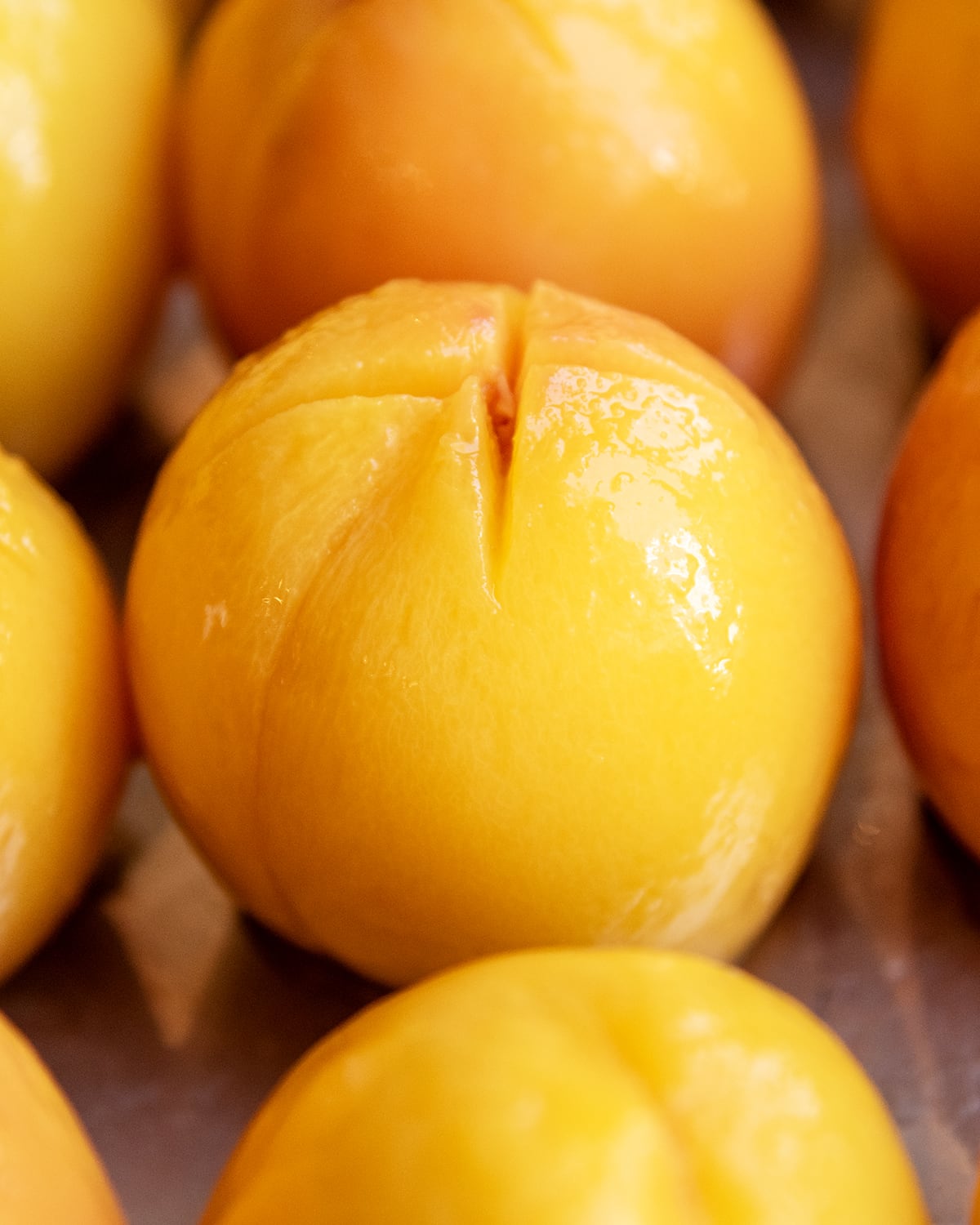A shiny peeled peach with an x cut out on the top.