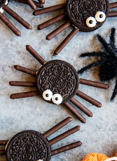 An Oreo spider with two candy eyes on top, and chocolate pocky sticks for the legs.